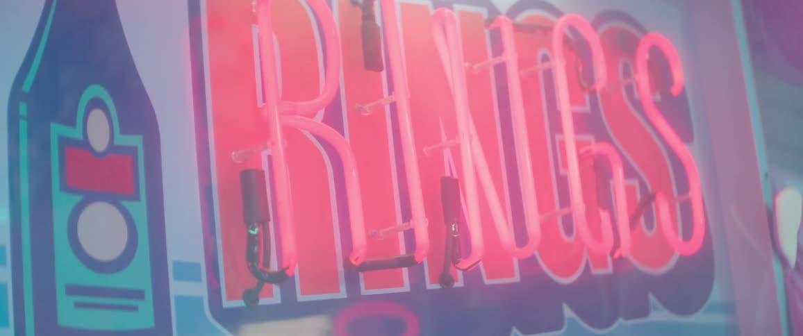 Neon pink sign with the word rings at an event