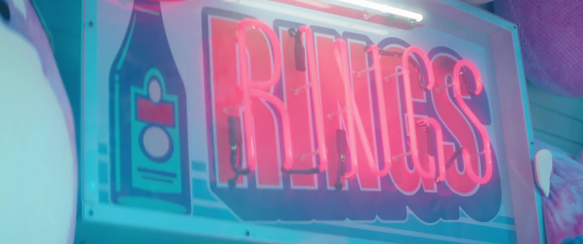 A neon sign is surrounded by stuffed animals
