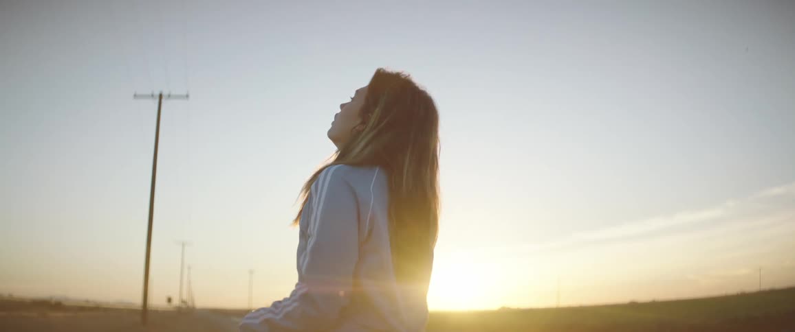 Woman wearing sports clothings walking near a rural road at sunset