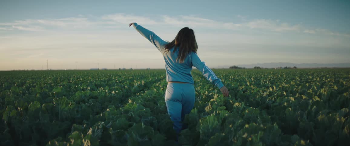 A woman is walking through a field of flowers