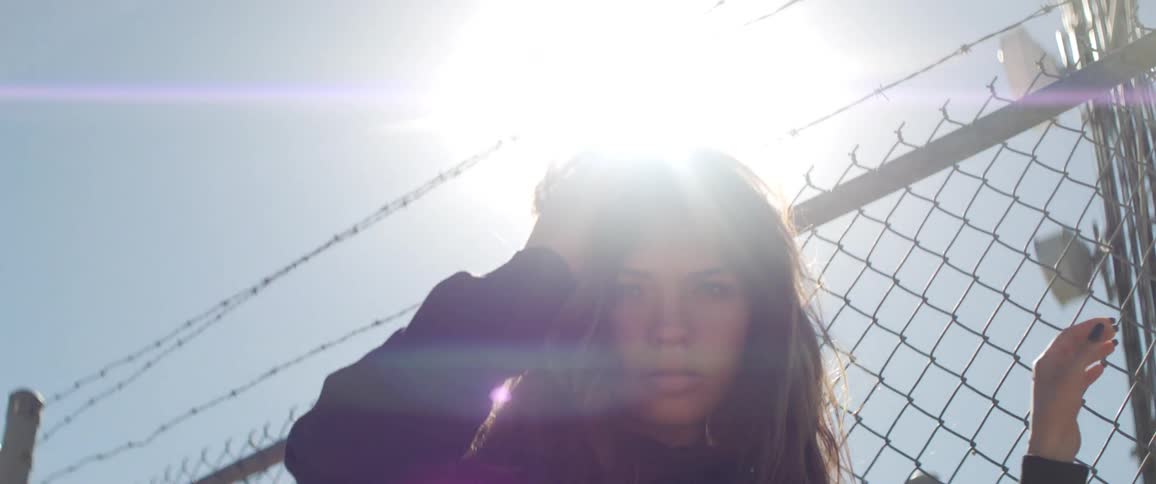 A woman looking somewhat menacingly in front of a fence