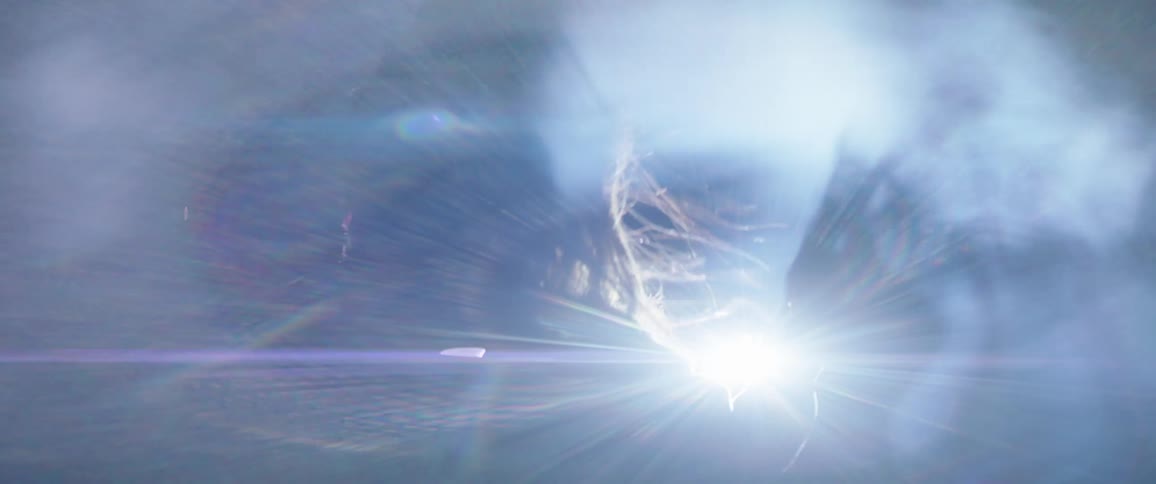 Silhouette of a woman standing in white smoke moving her hand around a light flare