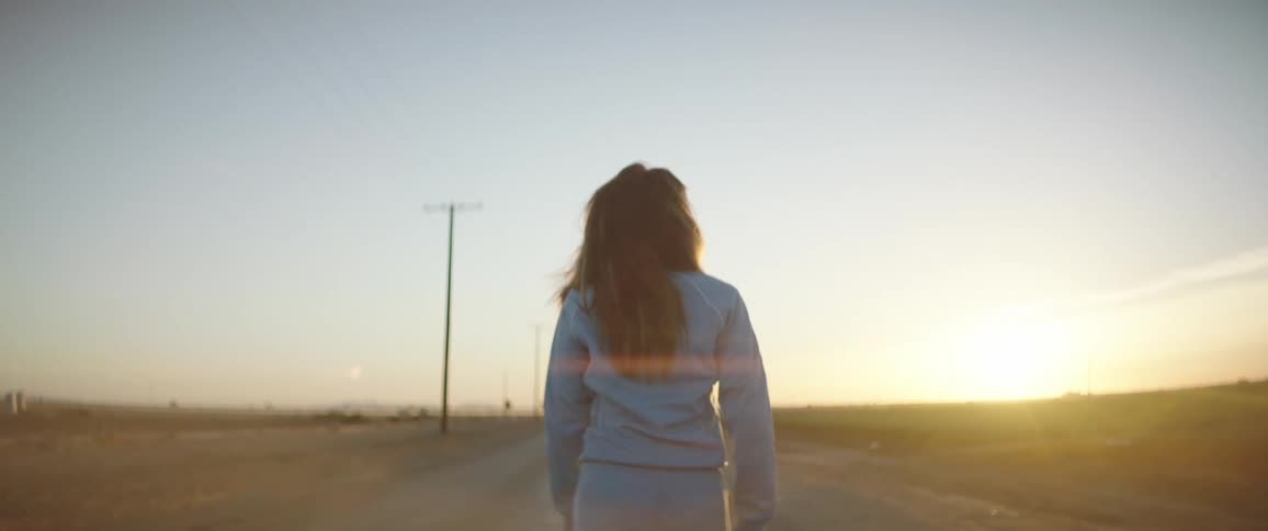 A woman is walking down the road at sunrise
