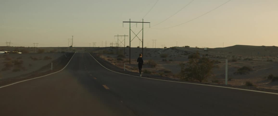 A person jobs on the side of a rural road with no buildings or vehicles in sight