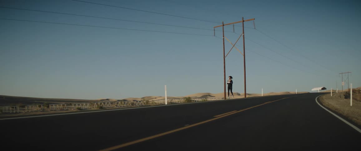 Young woman in sports clothing jogging in a road at morning