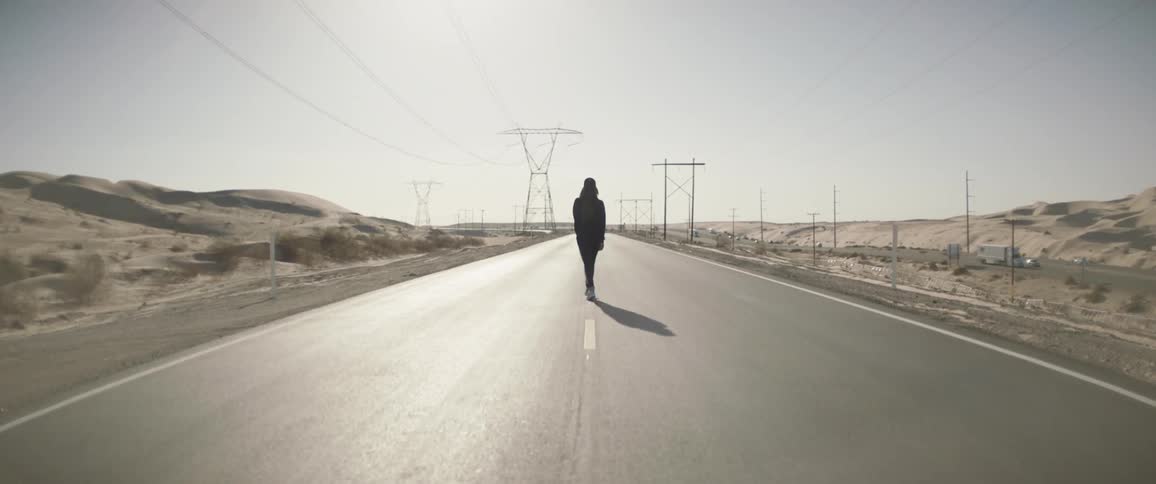 A person walks down the middle of the highway road