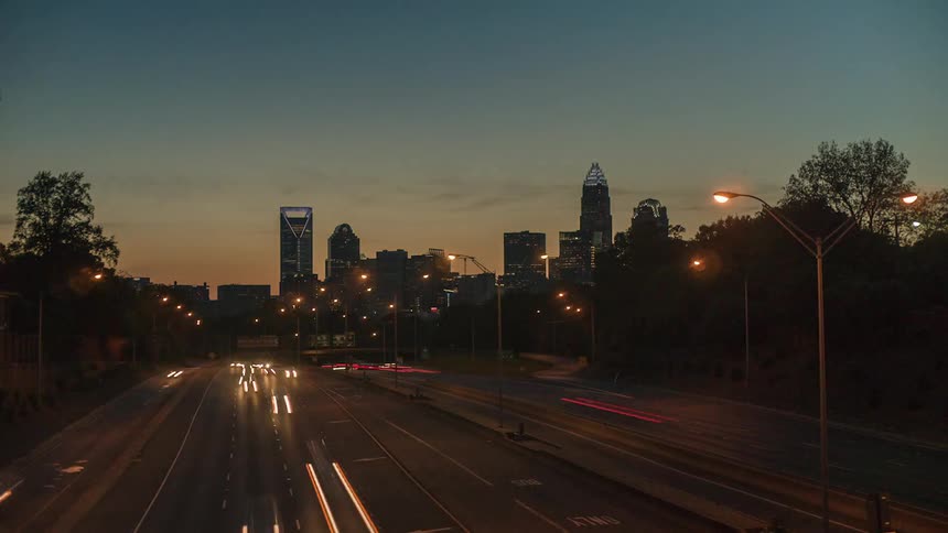 A highway with vehicles with buildings skyscrapers the sky and clouds in the background