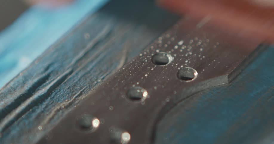Close up of a knife being sanded over a workbench