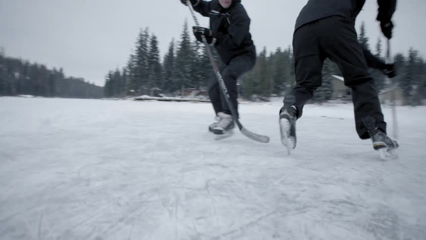 A man moves the puck past an opponent playing hockey