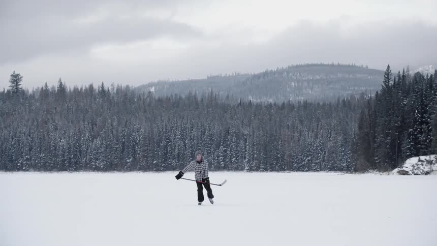 Man with hockey stick skating around on frozen lake