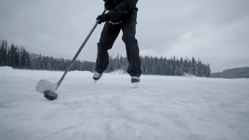 Man plays ice hockey outside on a cloudy day