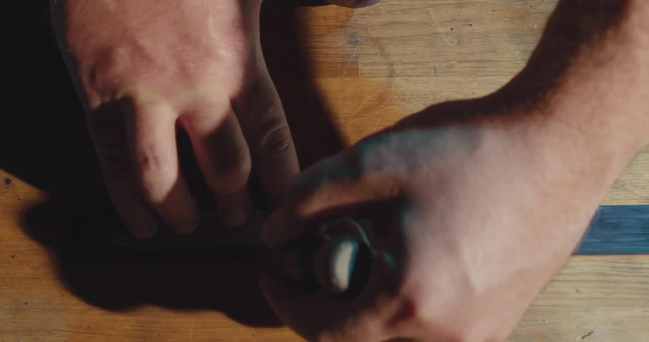A man with brown skin is cutting out the outline of a knife blade