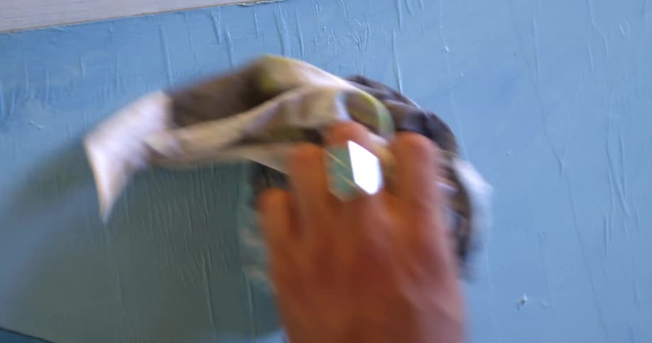 A painter swipes a brush and dabs a cloth to smooth paint on a canvas