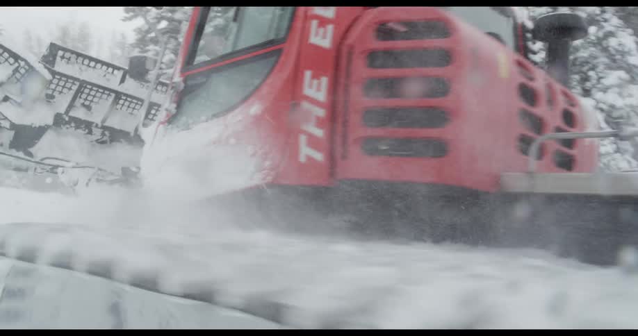 Snow plow plowing through heavy snow downhill in the mountains