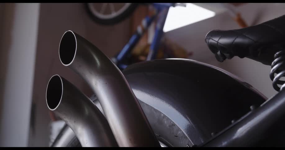 Pipe tubes on the back of a motorcycle parked inside of a bike shop