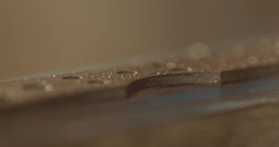 A craftsman dusting and sanding a piece of metal on the workshop