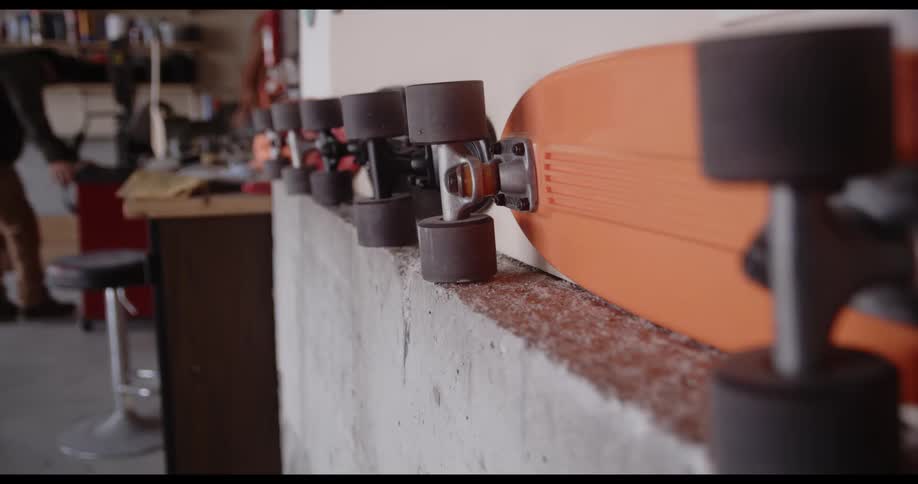 A workshop with skateboards with a man with a jacket and a hat pushing a cart in the background