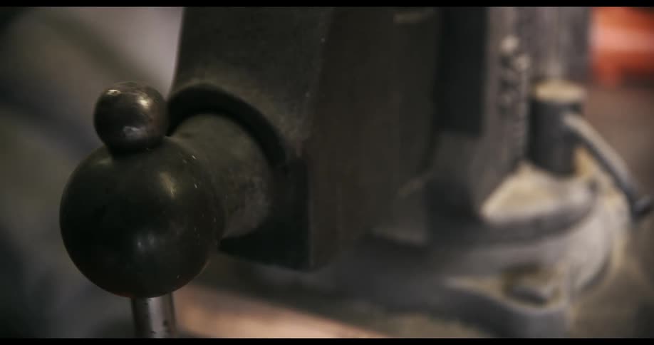 A person turning the handle on a metal vice