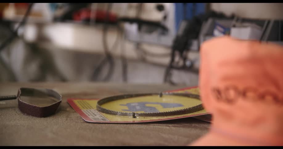 A man grabs a metalworking tool from a counter in his garage