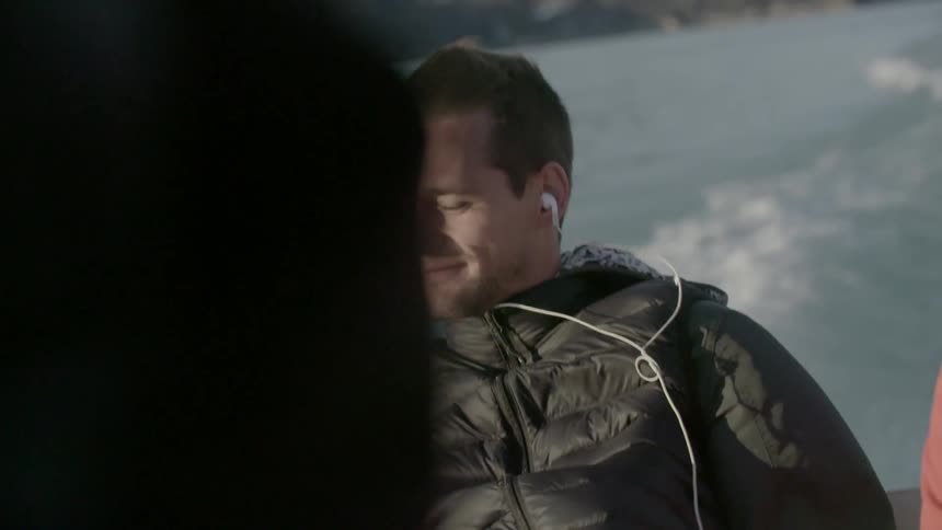 Man wearing earphones smiling while riding in a boat