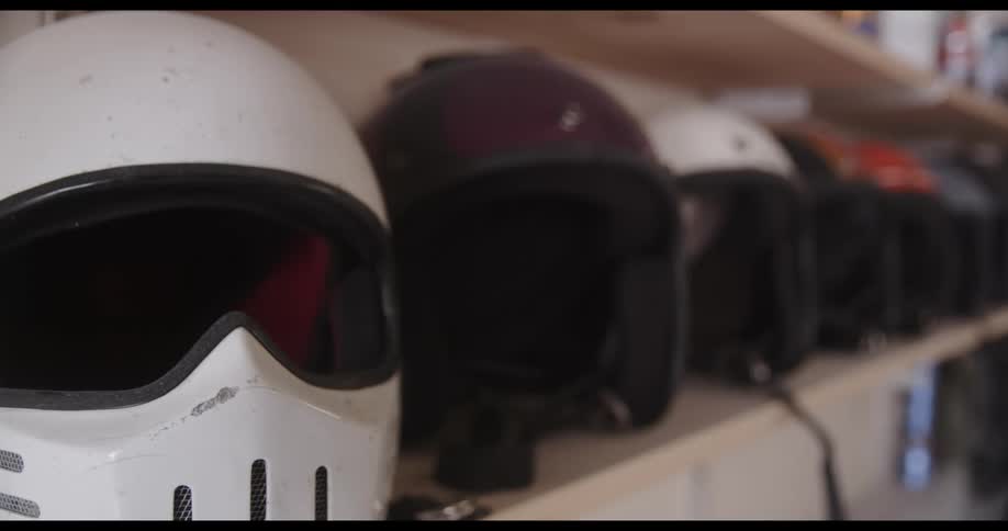 A shelf containing several different piolet helmets of different colors such as white black and red