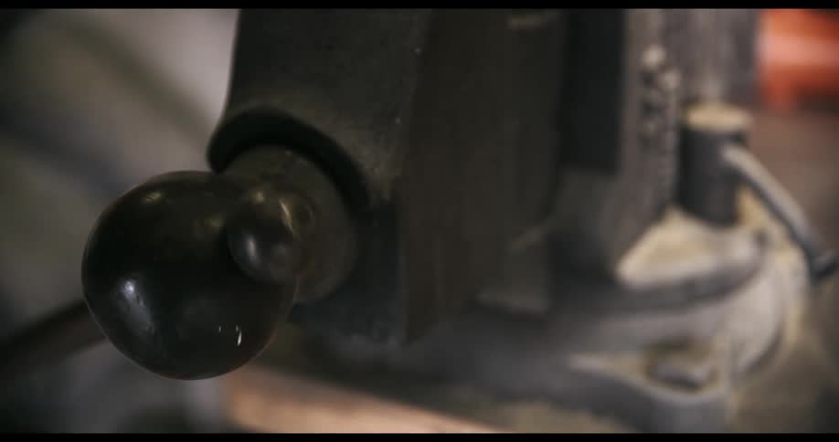 A hand adjusts the side of a vise