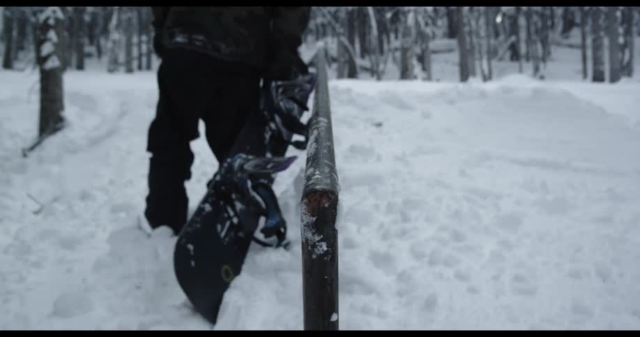 Man in black winter clothes walks in over the thick snow with a snowboard
