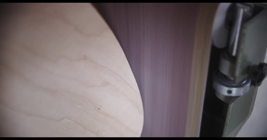 A person standing the board of a skate board with a belt sander
