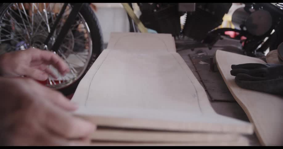 A man picks up cardboard pieces lying in front of a motorcycle