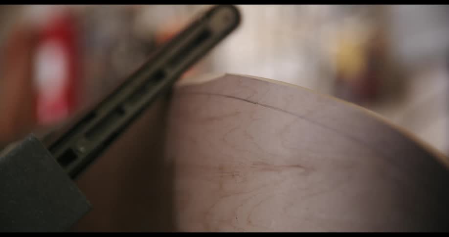 Person using a machine to shave pieces off of a piece of wood