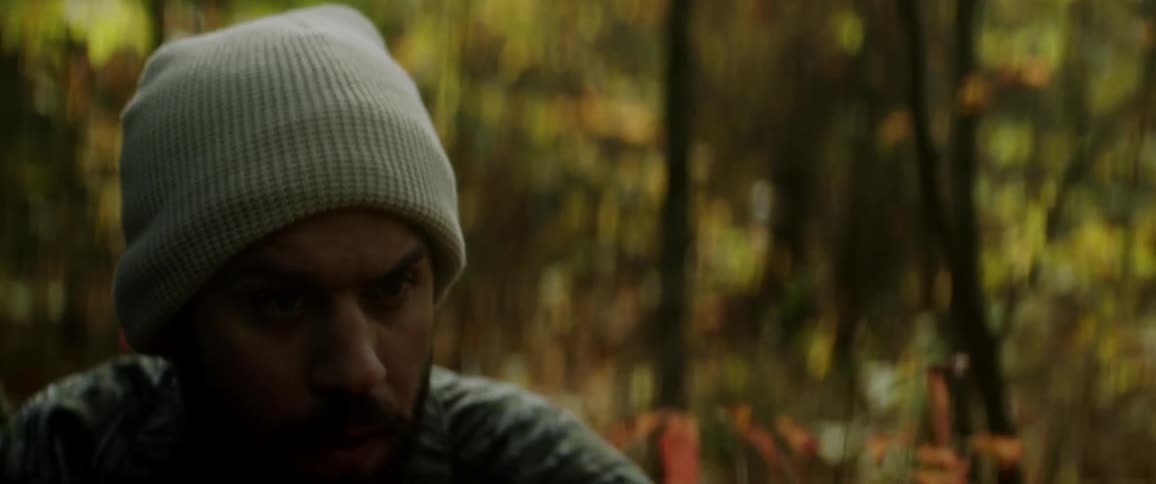 Man carefully walks through a forest and squats to a aim a rifle gun
