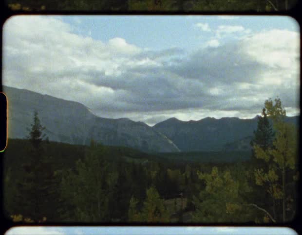 Mist covered mountains bordering forest under a cloudy sky