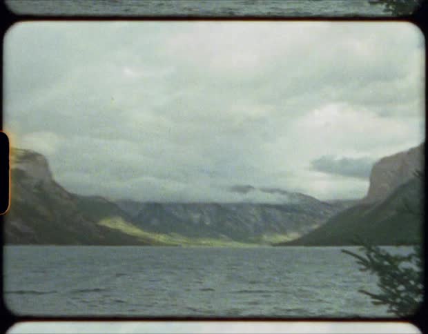 Calm waters of a lake near the mountains on film