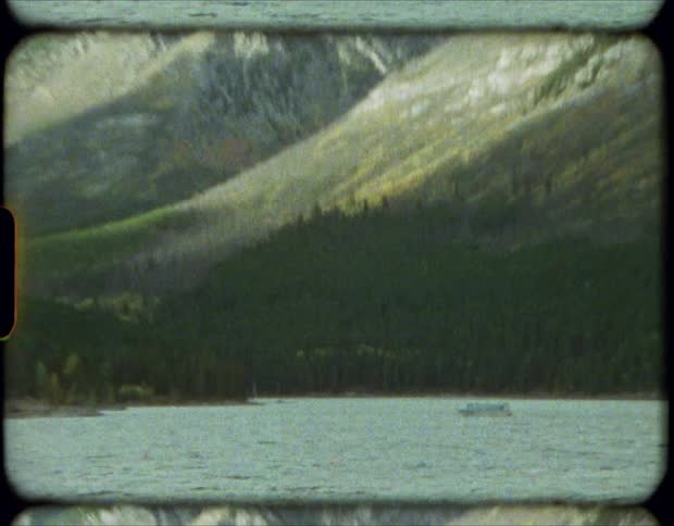 Boat in a lake near the snow covered peaks of a mountain range on film