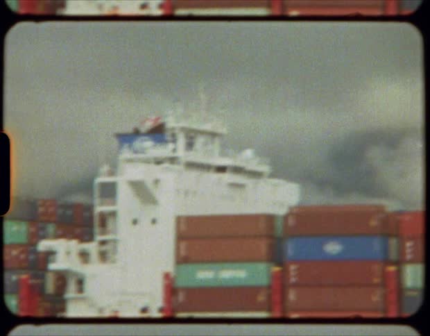 Freight containers stacked up on a dock and a ship at daytime
