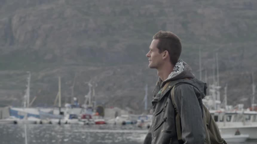 A man is walking along a pier looking over the water