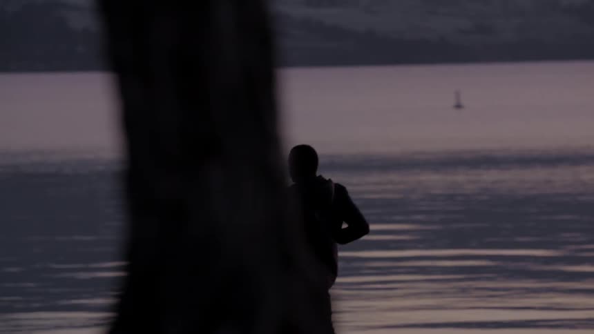 Man runs next to a lake at sunset