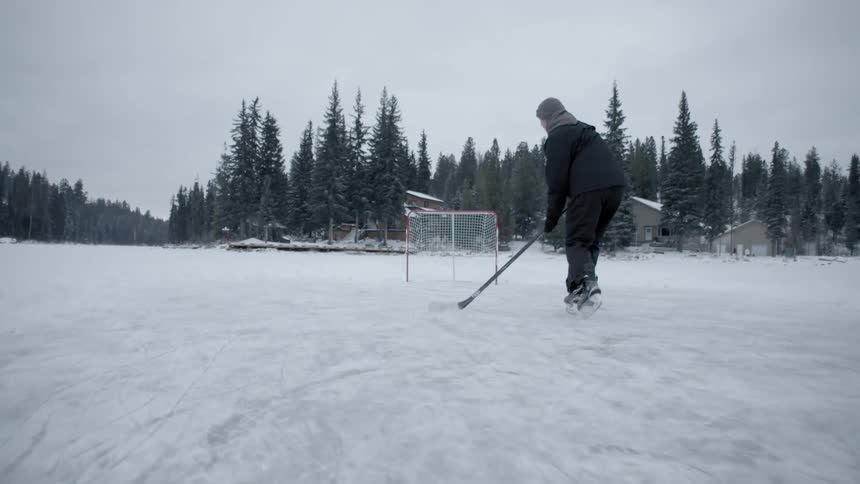 A man practices hockey on a snowy lake
