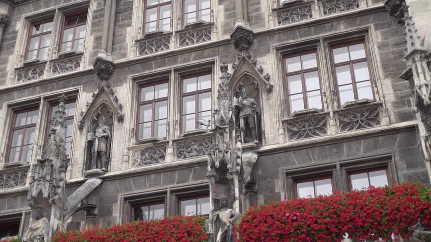 A tall building with many windows is decorated with statues and interesting architecture