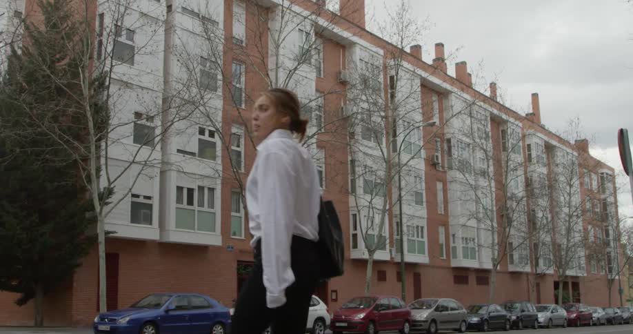 A woman stands at a street corner before stepping off to cross the street