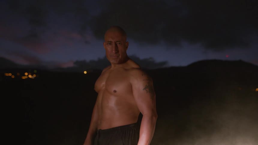Shirtless man staring at the camera outside at nighttime