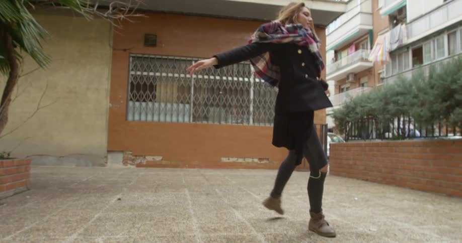 Young woman dancing ballet in front of an apartment building in town