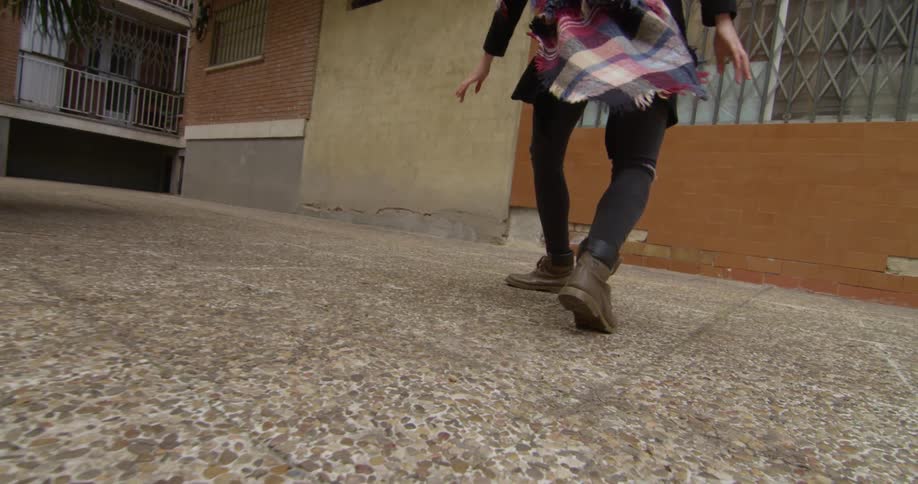 Dancer moves across paved yard of apartment building