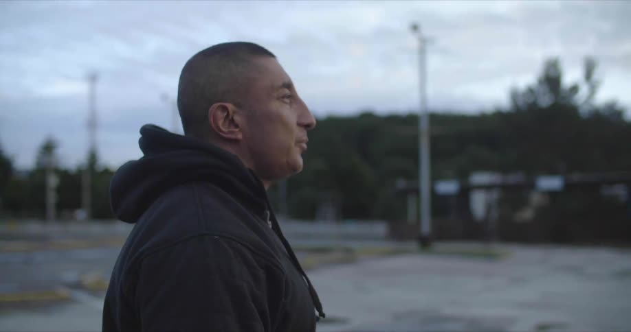 A man walks in a quiet store parking lot away from the building