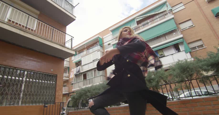 A teenage girl spins around in a neighborhood