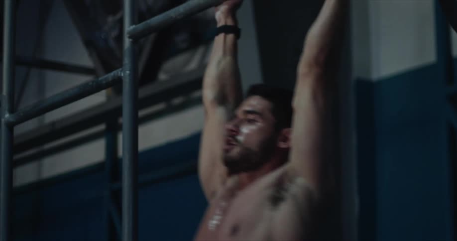 A man completes pull ups on a bar inside a gym