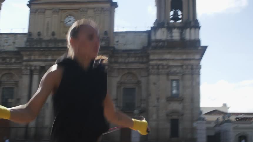 A woman jumping rope out in front of a building at daytime