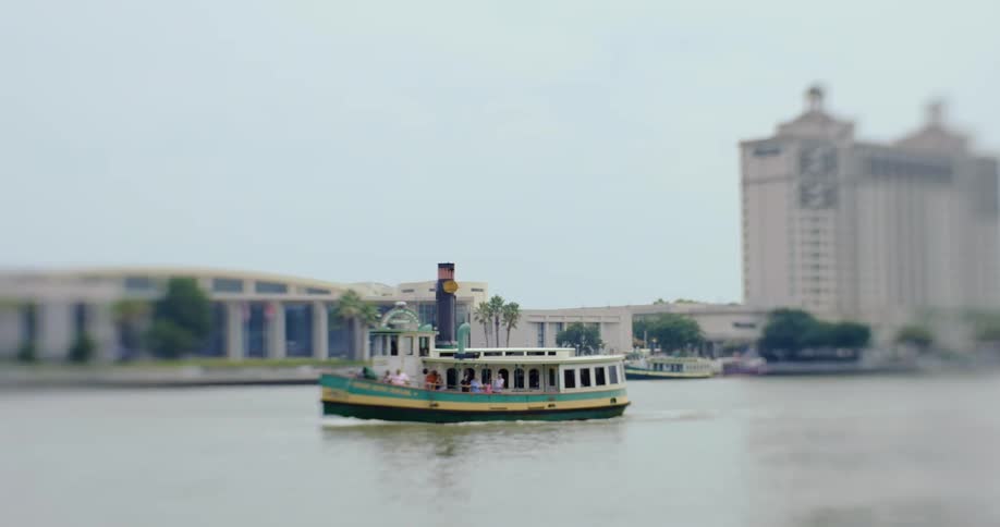 River boat carrying passengers down a river next to a city