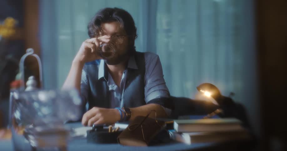 Man sitting down drinking from a glass with brown alcohol