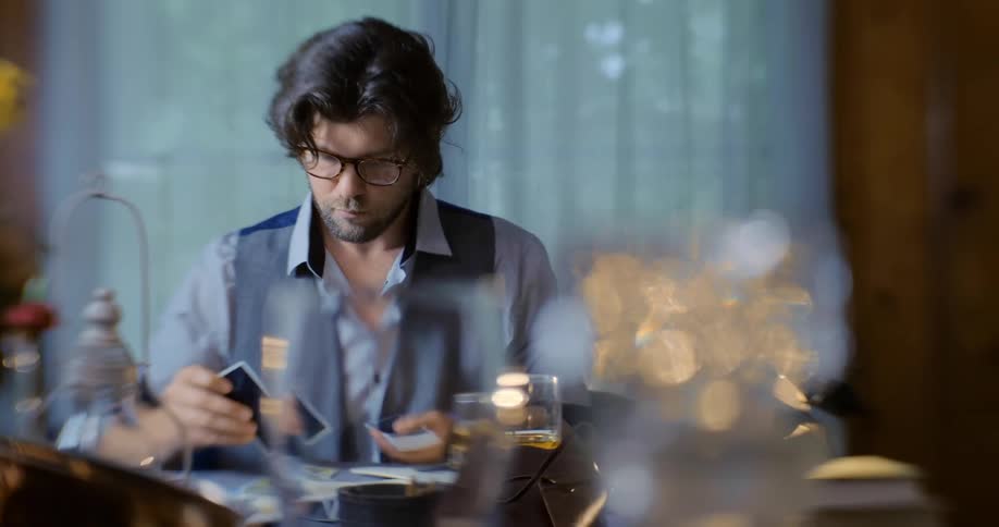A man is sitting at a table placing cards from a deck onto it